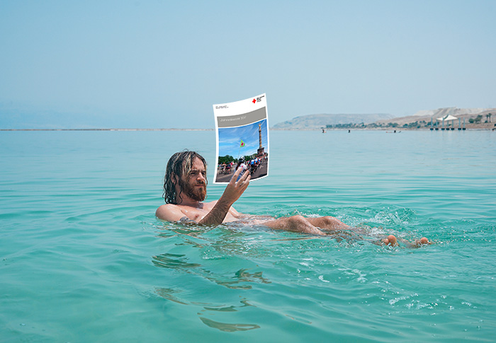 Mann im Toten Meer liest entspannt den Jahresbericht vom Berliner Roten Kreuz