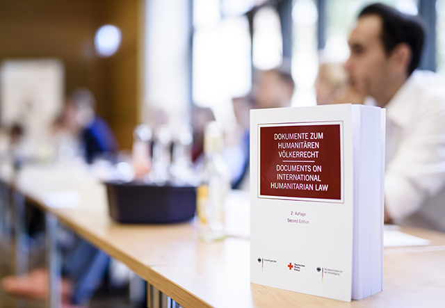 Das Humanitäre Völkerrecht ist ein besonderes Recht während eines Krieges Buch "Humanitäres Völkerrecht" steht auf Tisch.