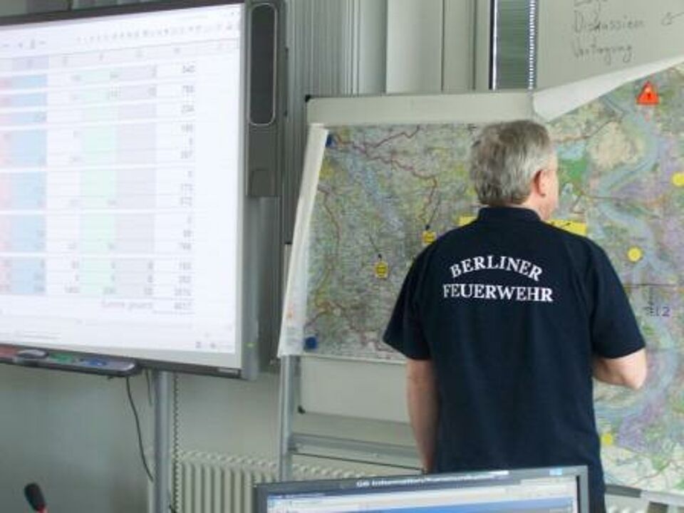 Mitglied der Berliner Feuerwehr trägt etwas in eine Karte ein