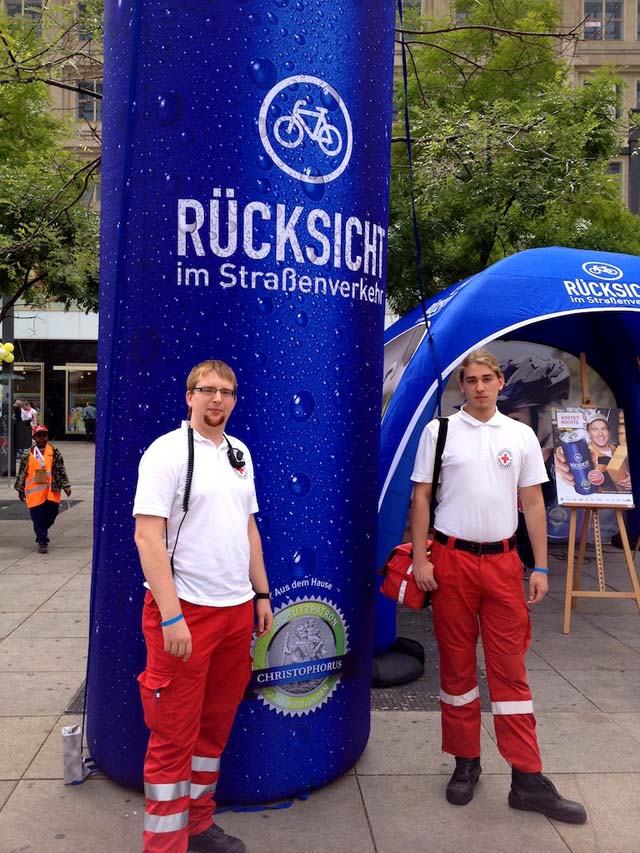 Zwei Sanitäter vor einem Infostand Zwei Sanitäter vor einem Infostand